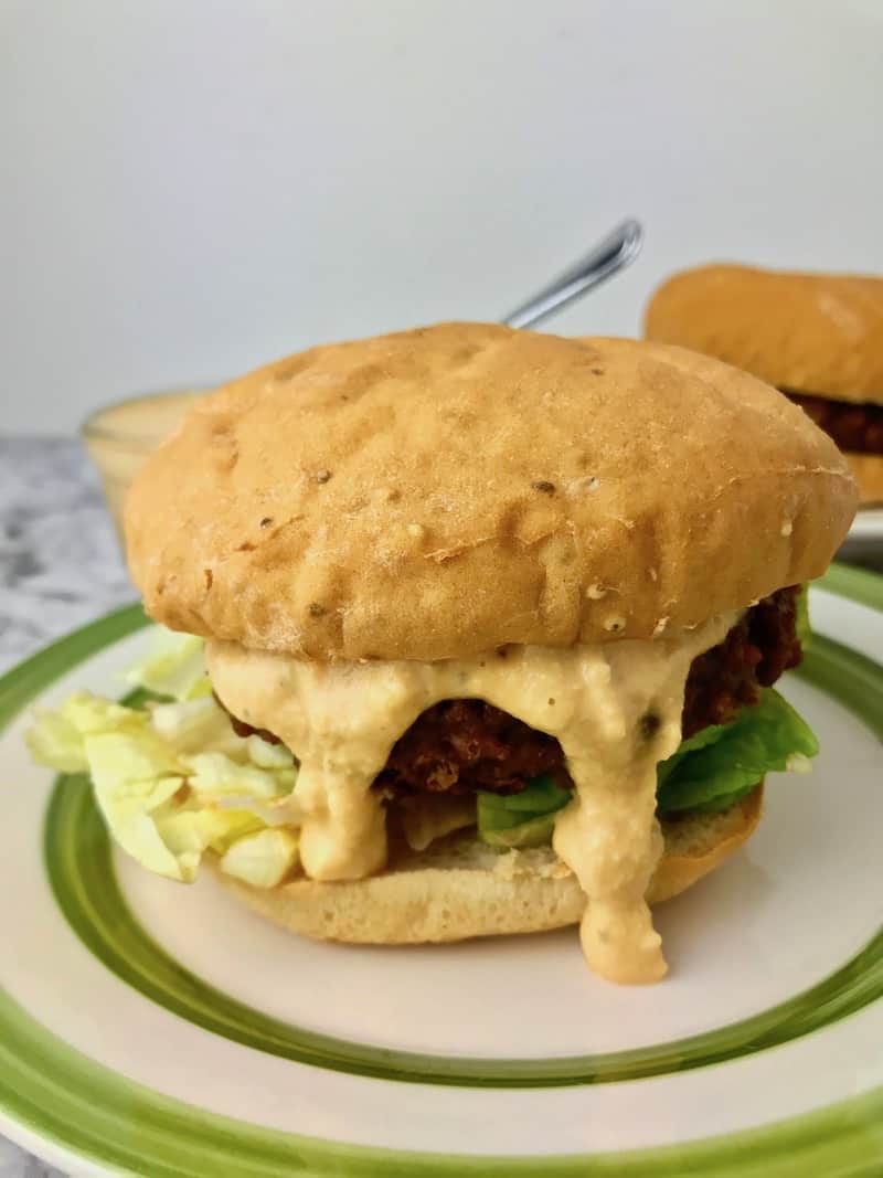 Burger sauce dripping out of a burger on a plate.