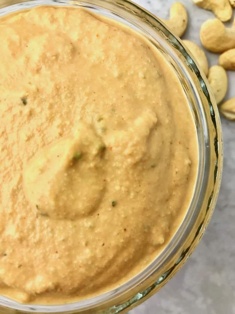 A small bowl of orange vegan burger sauce.