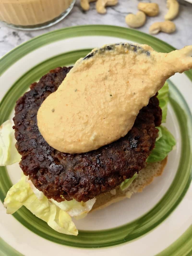 Burger sauce being spooned onto a burger patty.