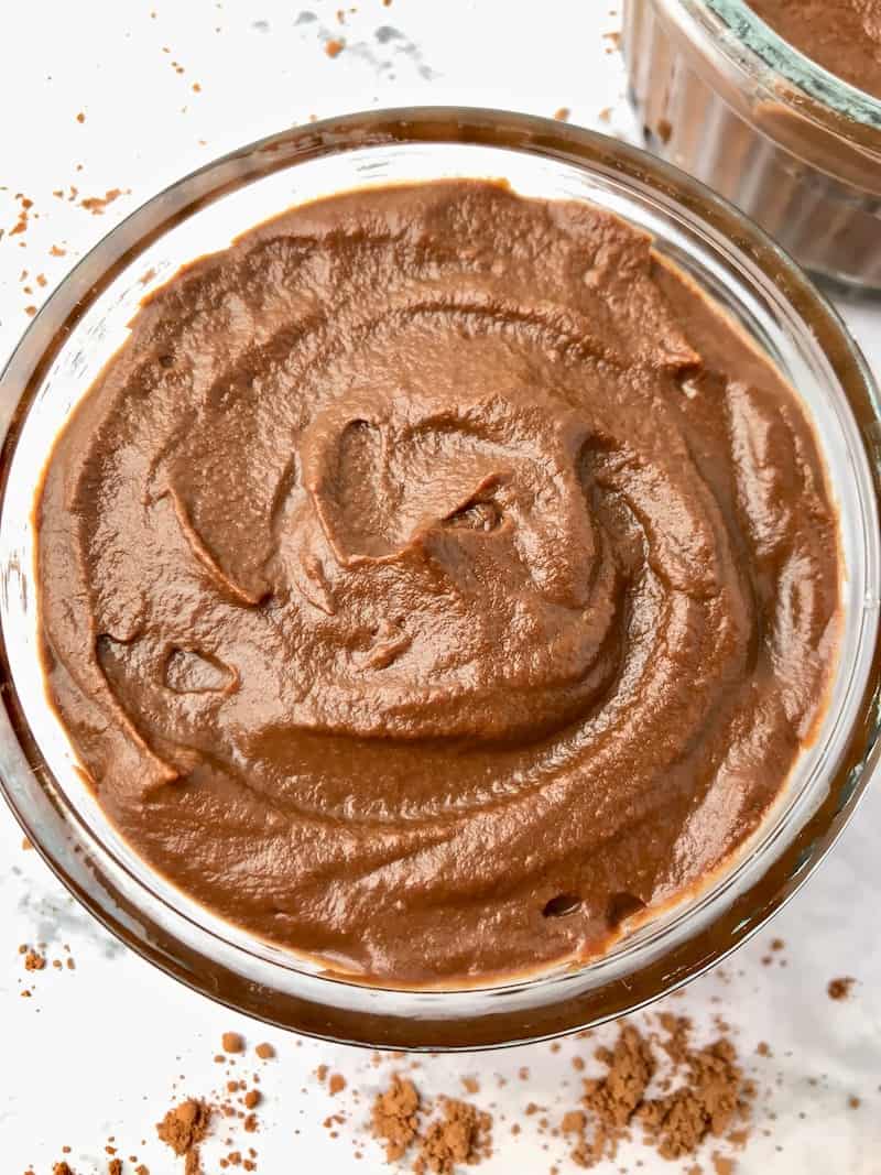 A bowl of chocolate sweet potato pudding with cacao powder sprinkled next to it.