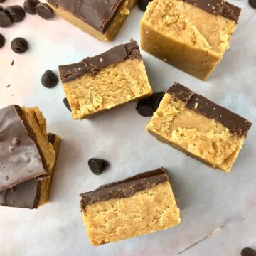 Chocolate peanut butter bars and chocolate chips spread out on a surface.