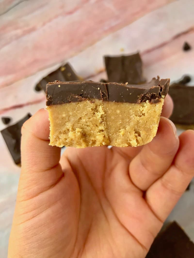 A hand holding a chocolate peanut butter bar.