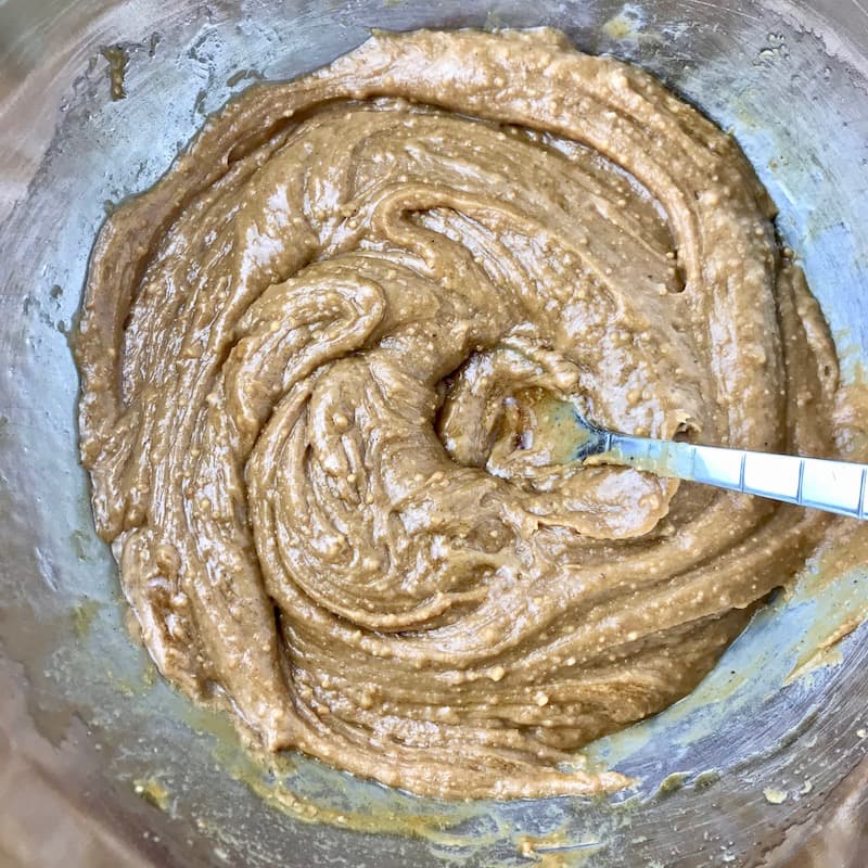 Peanut butter and maple syrup mixed together in a bowl with a spoon.