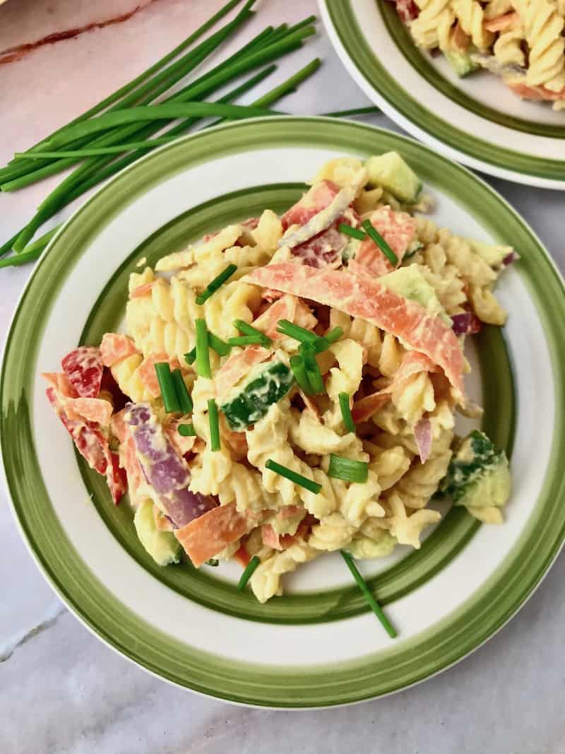 Pasta salad on a plate next to some chives.