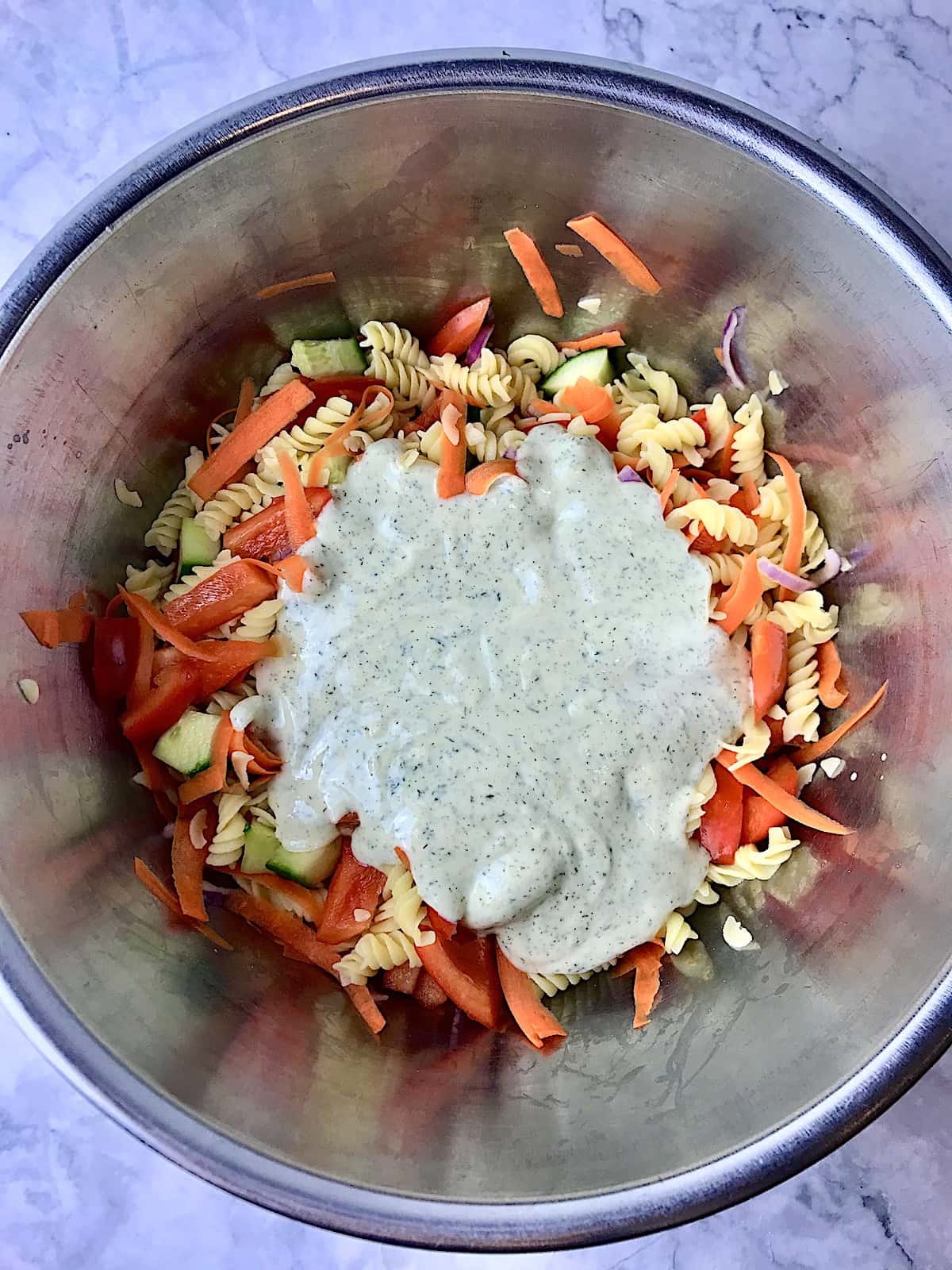 A bowl of pasta salad with hummus dressing poured on it.