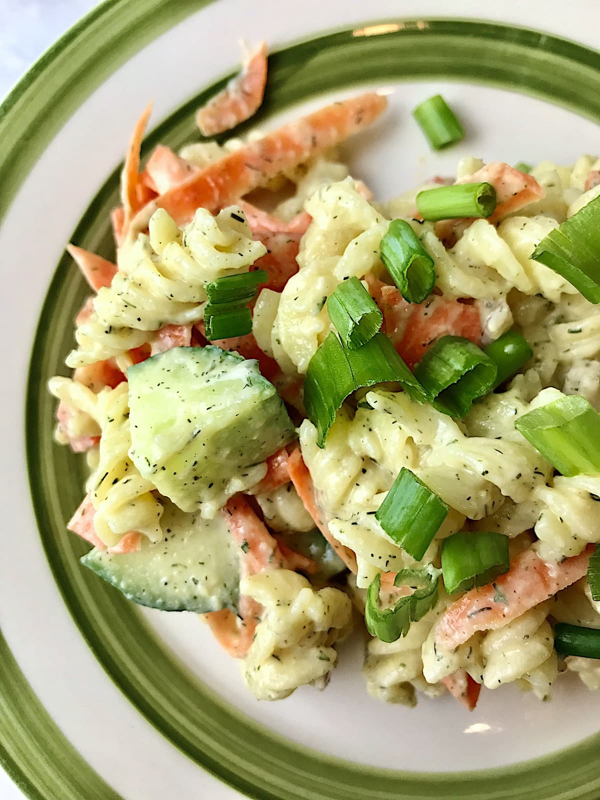 A plate of hummus pasta salad topped with chopped green onion.