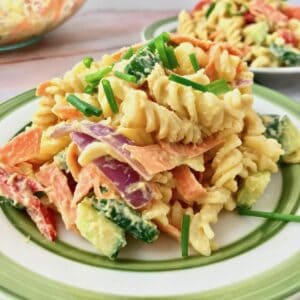 A plate of hummus pasta salad topped with chopped chives.