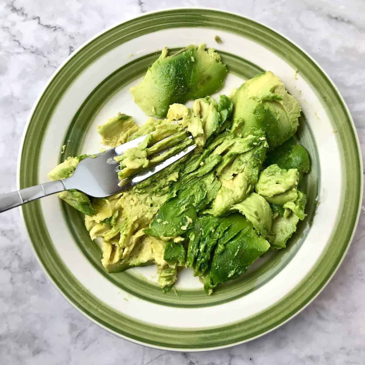 Avocado on a plate with a fork.