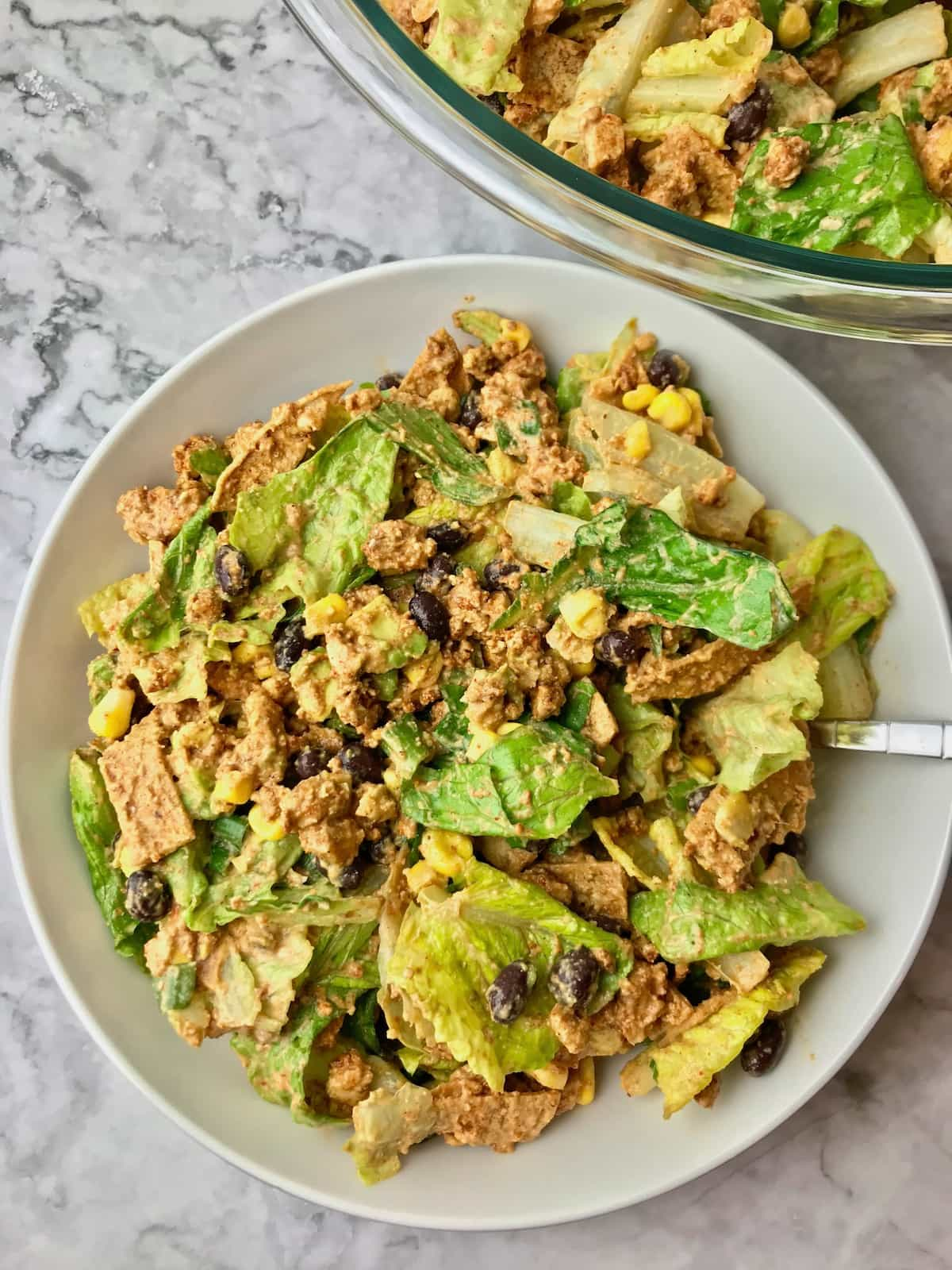 A bowl of vegan taco salad with a fork in it.