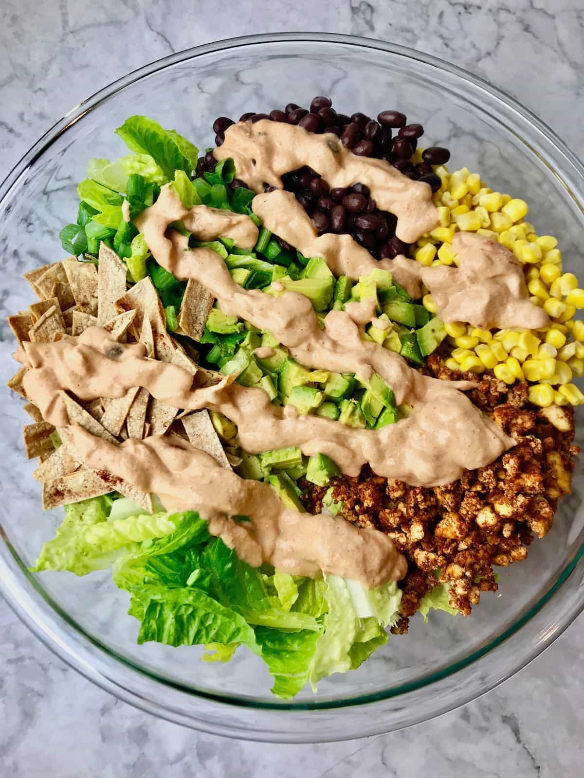 Taco salad ingredients topped with dressing.