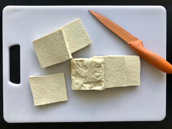 Slices of tofu on a cutting board.