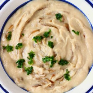 A white bean onion dip topped with fresh herbs.