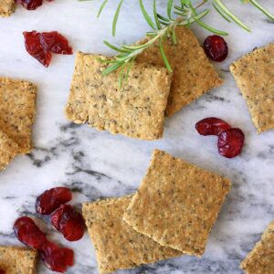 Crackers on a surface next to some cranberries.