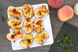 Peach bruschetta next to some whole peaches.