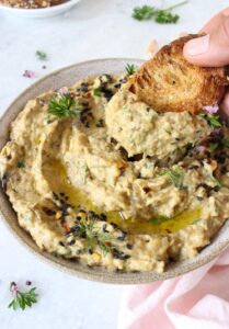 A vegan baba ganoush with bread dipped into it.