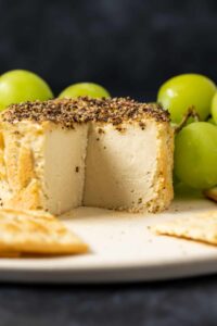 Vegan camembert cheese that has a slice cut out.