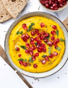 Carrot hummus topped with pomegranate seeds.