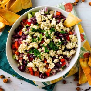 Seven layer Mediterranean dip surrounded by pita chips.