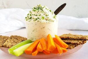 Garlic vegan cream cheese next to raw veggies and crackers.