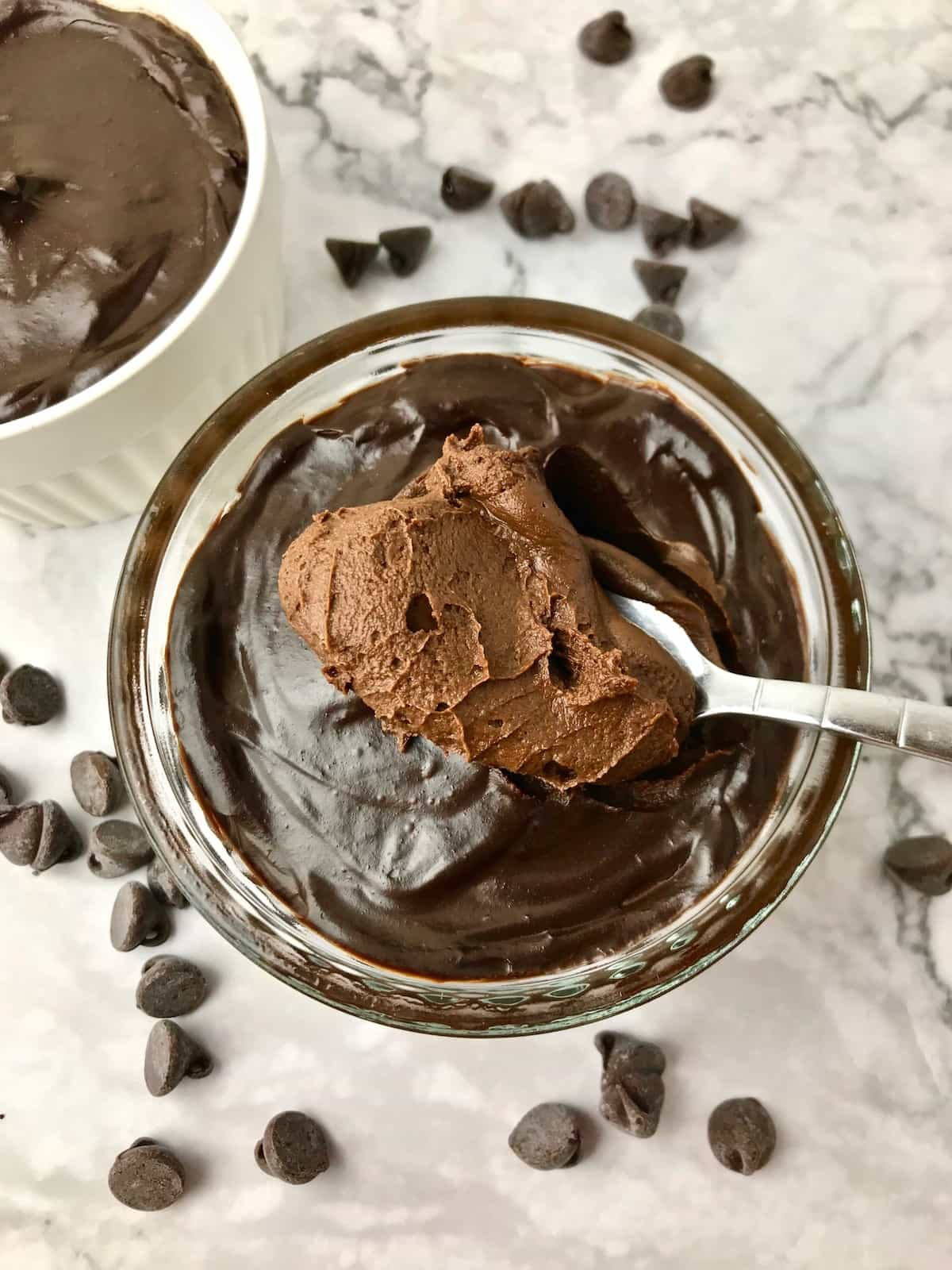 A spoonful of chocolate avocado mousse surrounded by chocolate chips.