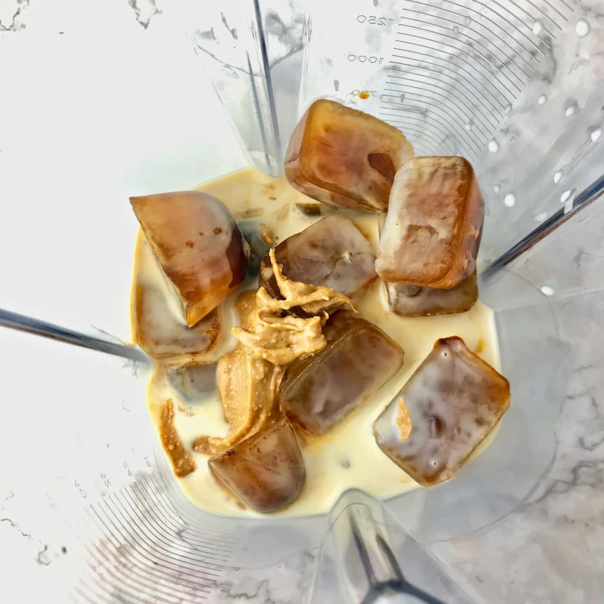 Frozen coffee cubes, peanut butter, and oat milk in a blender.