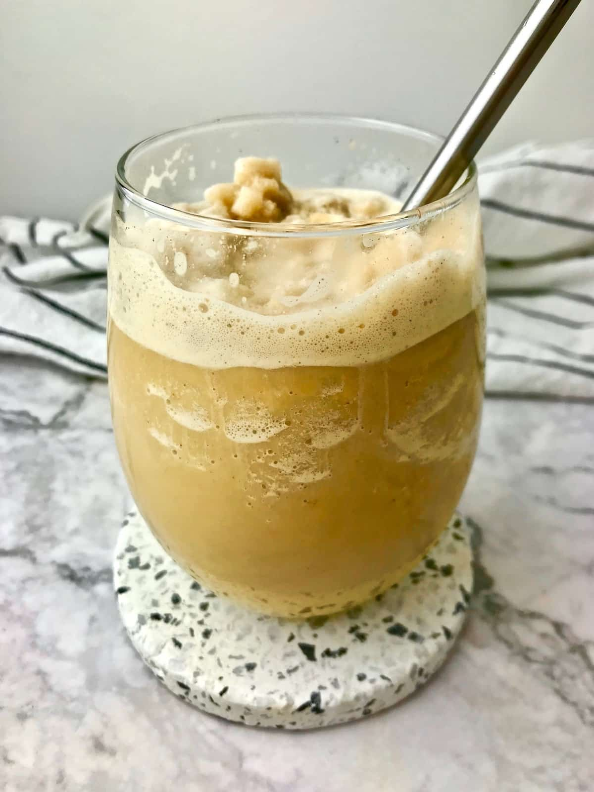 A frozen coffee in a stemless wine glass with a metal straw in it.