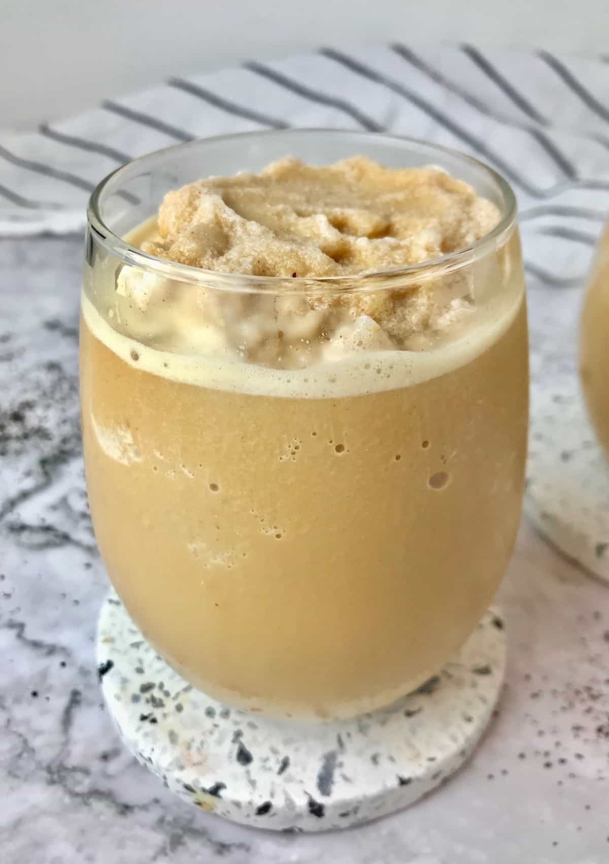 A stemless wine glass of frozen peanut butter coffee, sitting on a coaster.