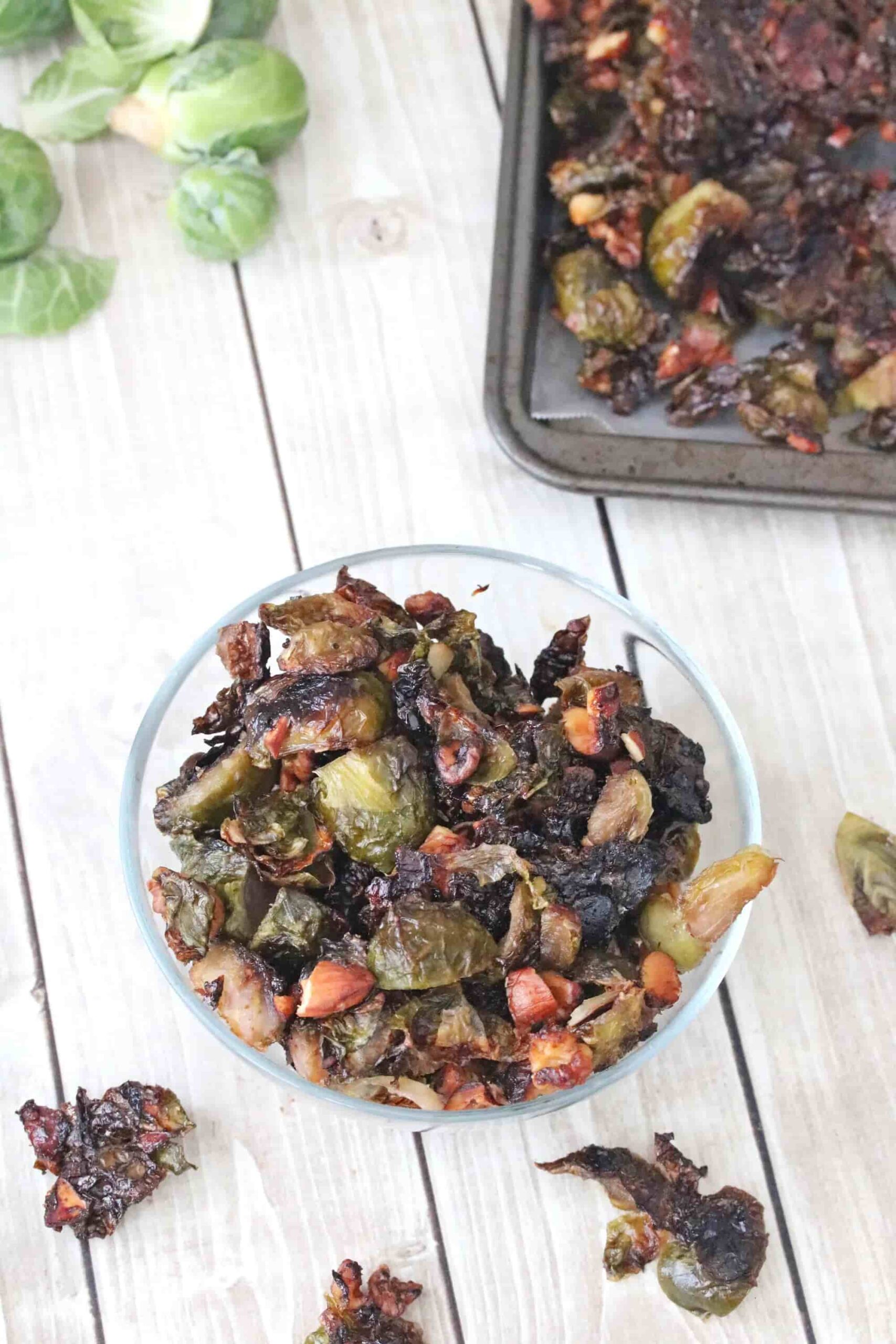 A bowl of brussels sprouts next to a pan of them.