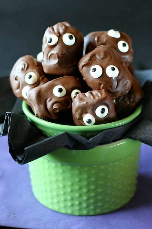 A container of chocolate candies with candy eyes.