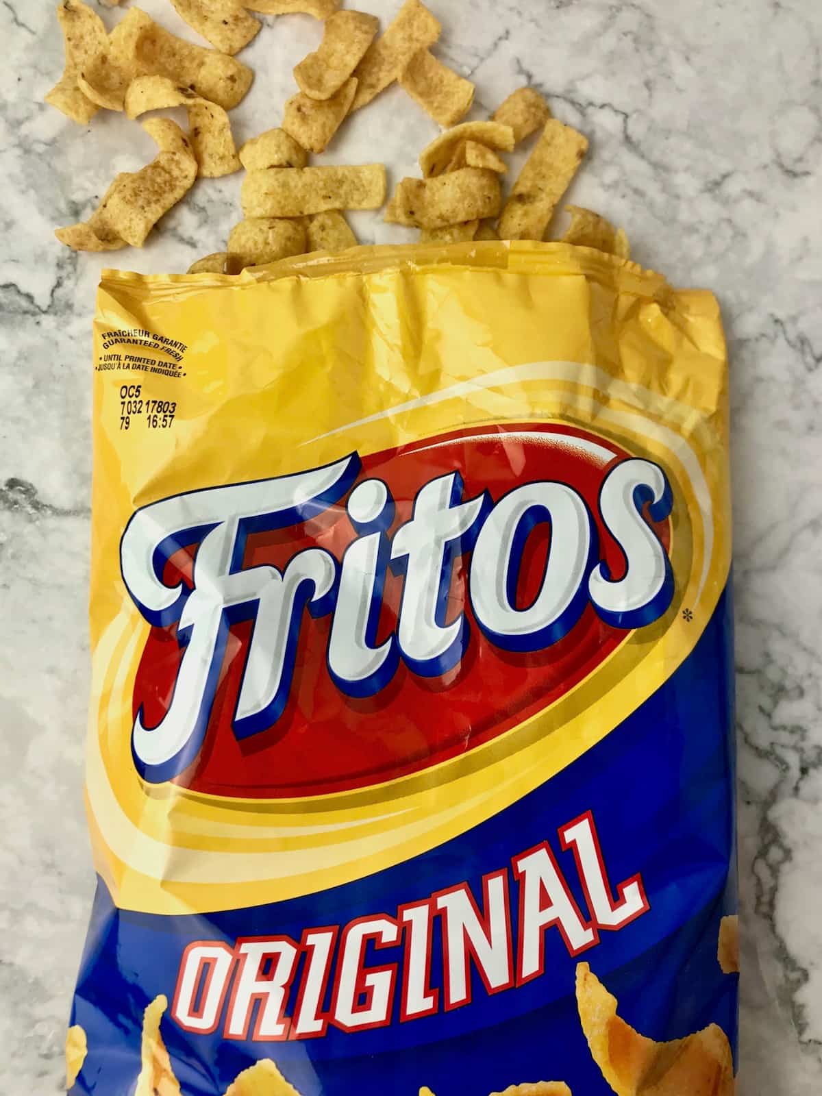 An open bag of Original Fritos with chips coming out the top of the bag.