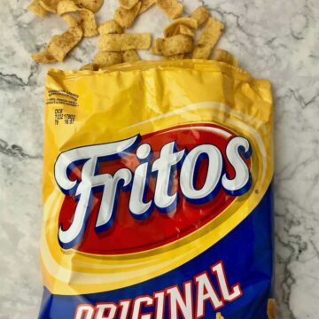 An open bag of Fritos with some of the corn chips coming out the top of the bag.