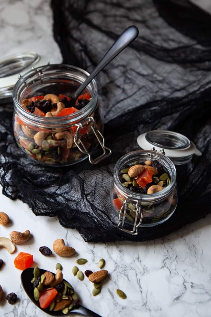 Two glass containers of Halloween-colored trail mix.