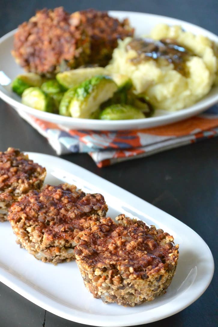 Three lentil muffins in front of a plate of Thanksgiving dinner.