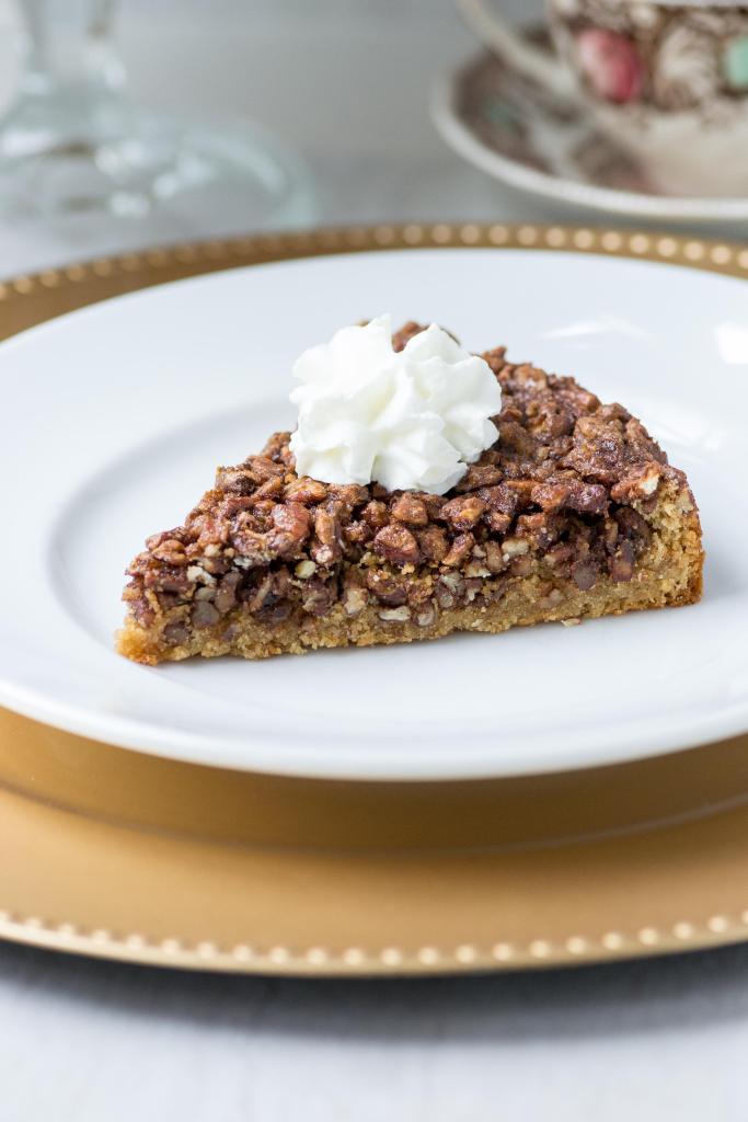 A slice of pecan blondie pie with whipped cream on top.