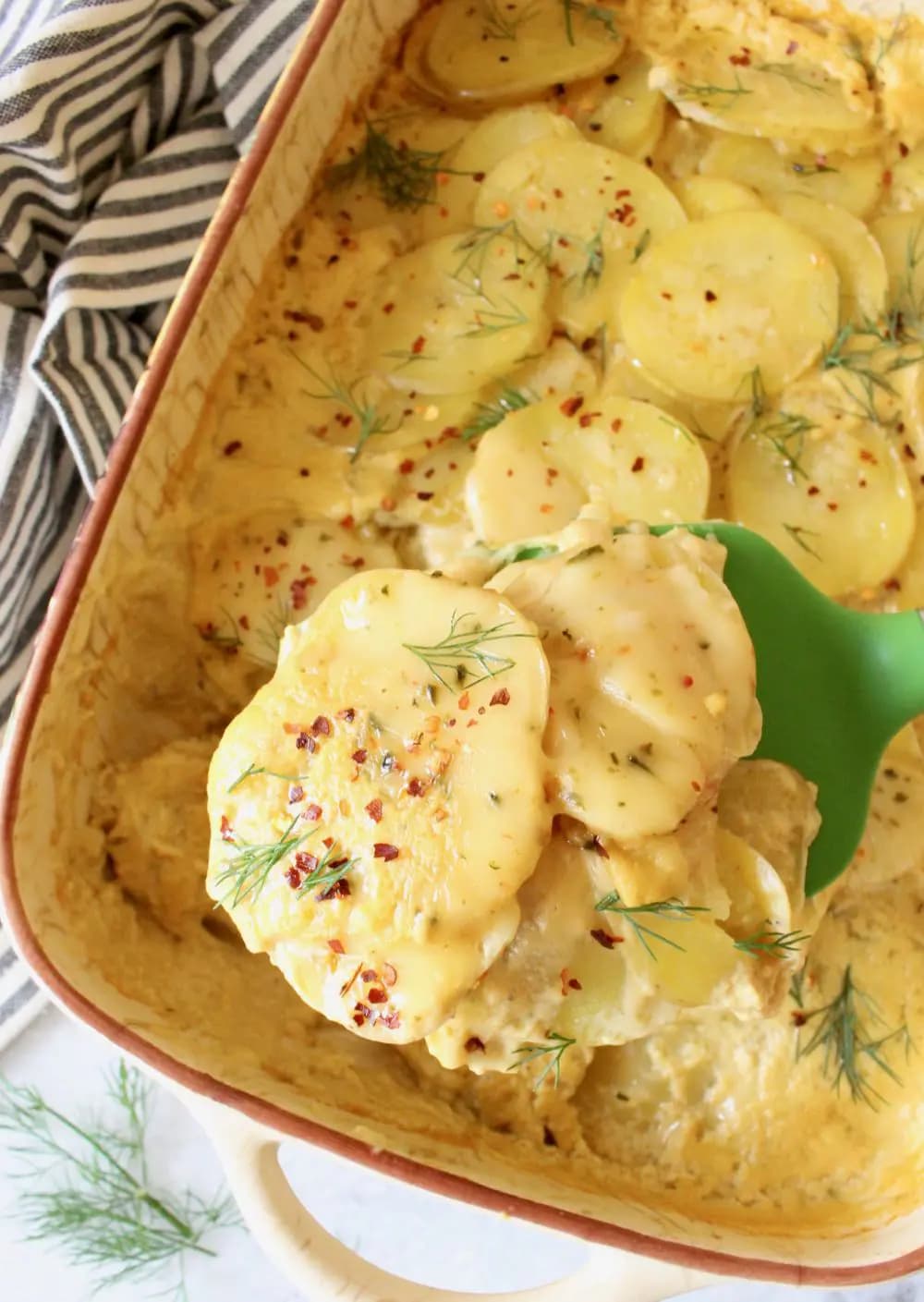 A pan of vegan scalloped potatoes with a spoonful over top.