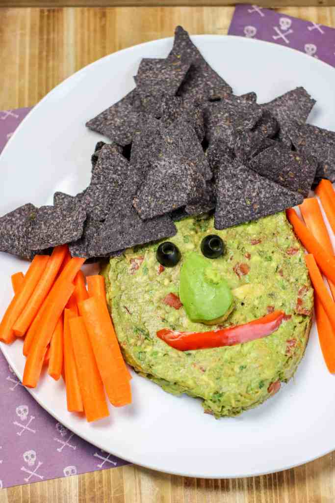 Guacamole, chips, and veggies in the shape of a witch face.