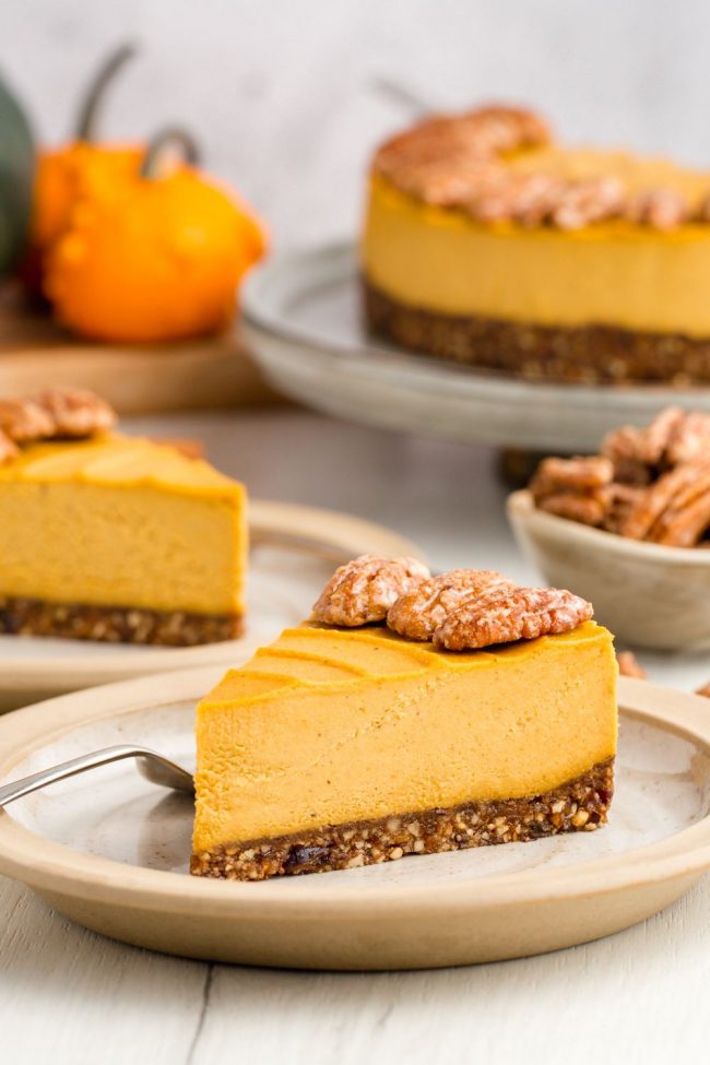 A slice of pumpkin cheese cake with more slices seen in the background.