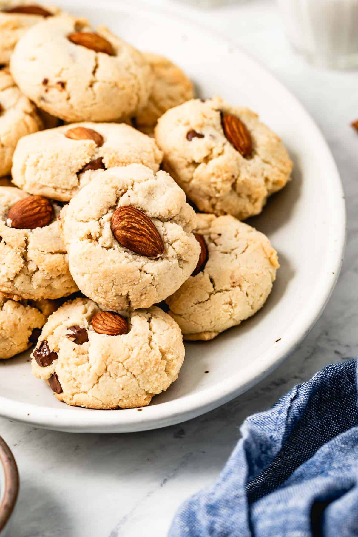 A plate of almond flour cookies each with an almond in the center.