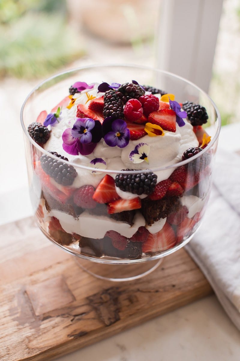 A vegan trifle with layers of berries, whipped cream, and chocolate cake.