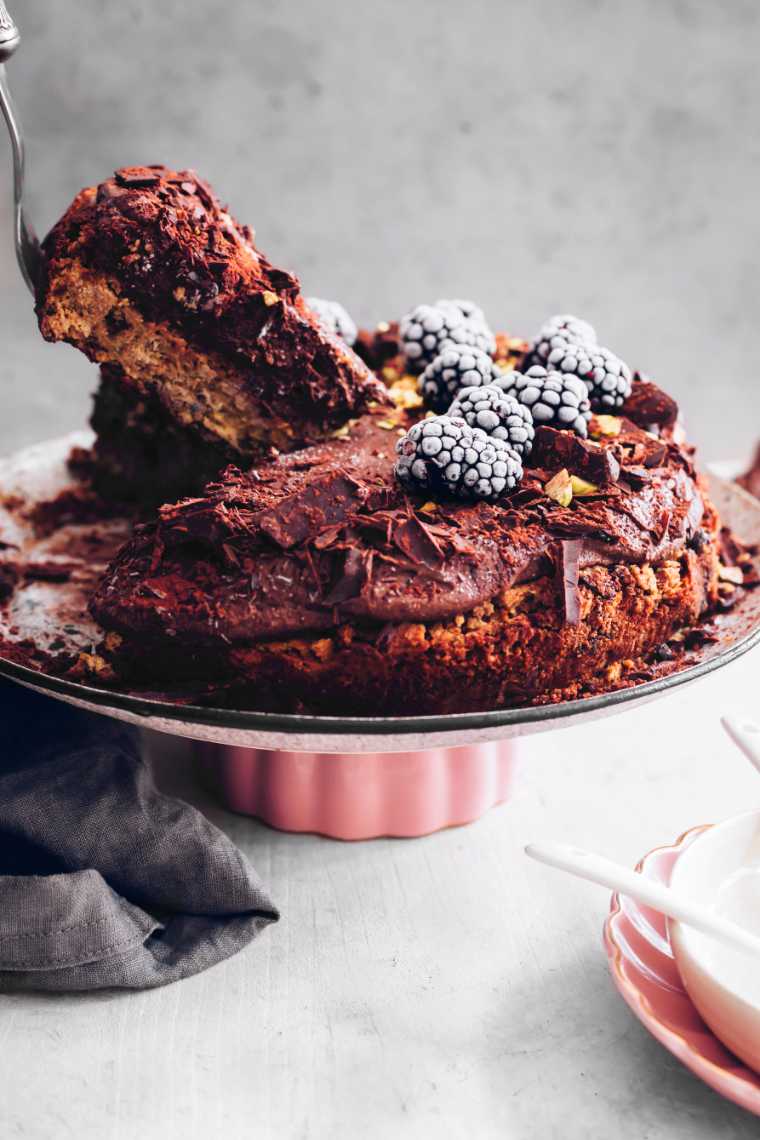 A vegan chocolate mousse cake with a slice being removed.