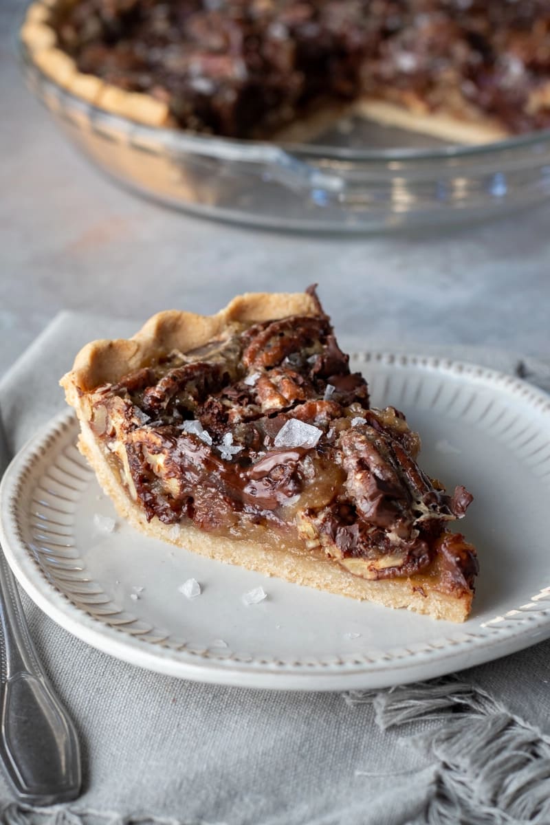 A slice of pie with pecans and salt flakes on it.