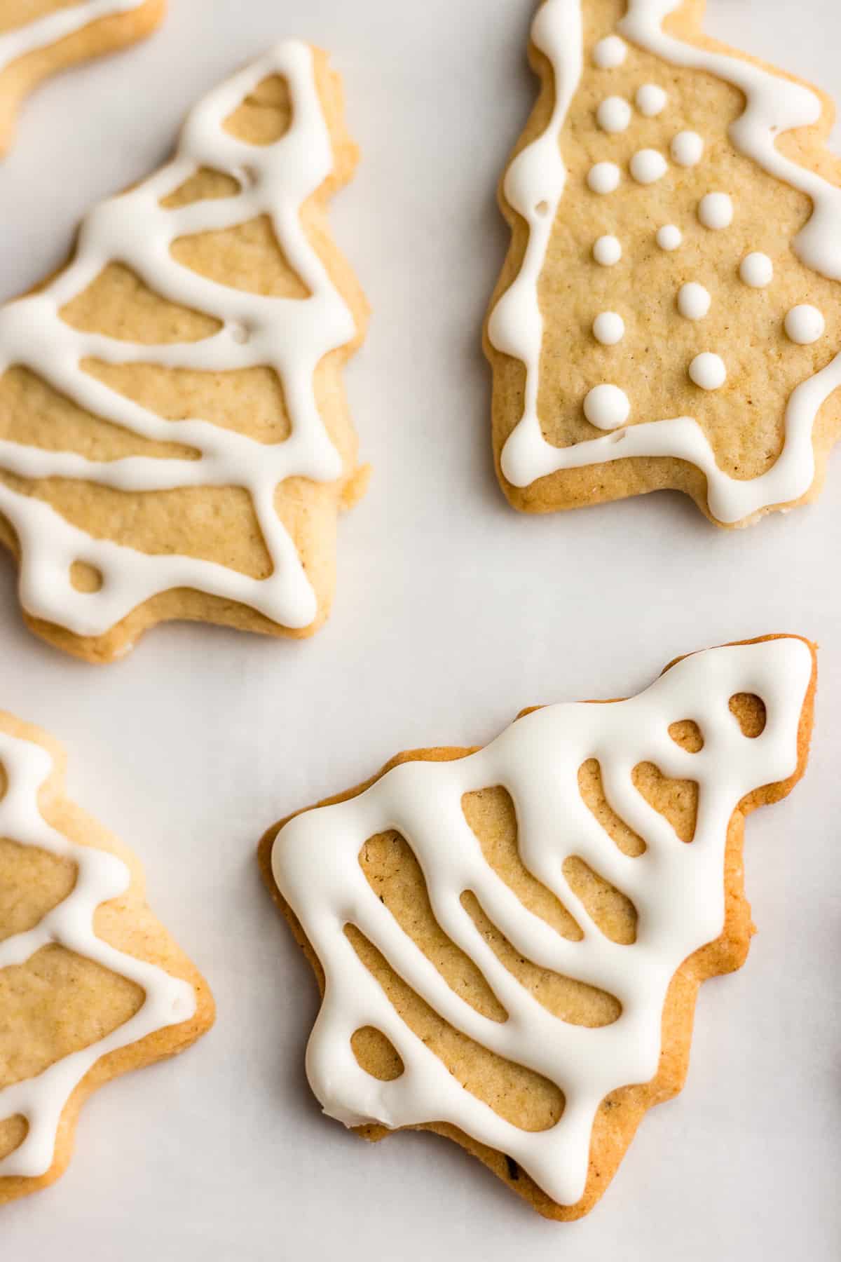 Ginger cookies in the shape of Christmas trees, with white icing on them.