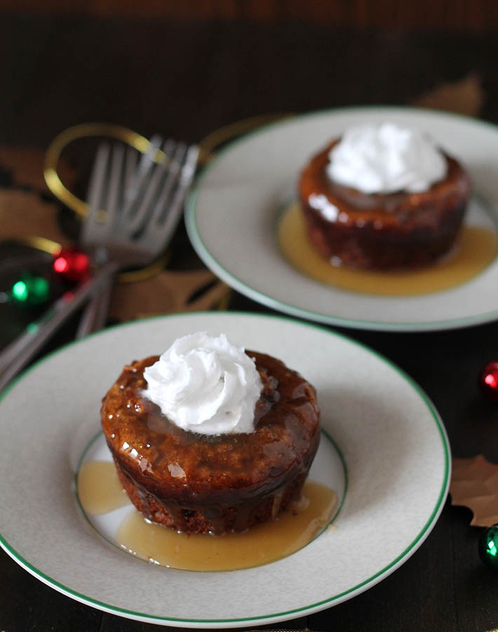 Two plates of sticky toffee pudding topped with whipped cream.