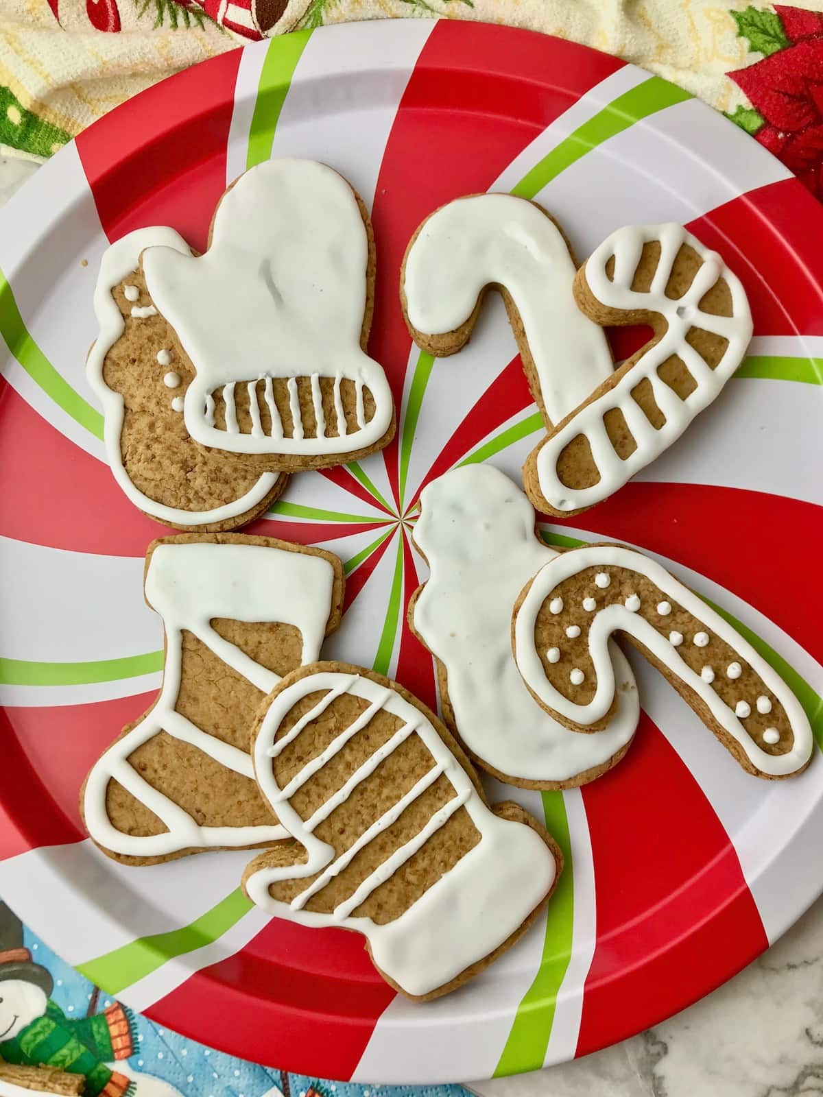 A plate of Christmas shaped sugar cookies with white icing.