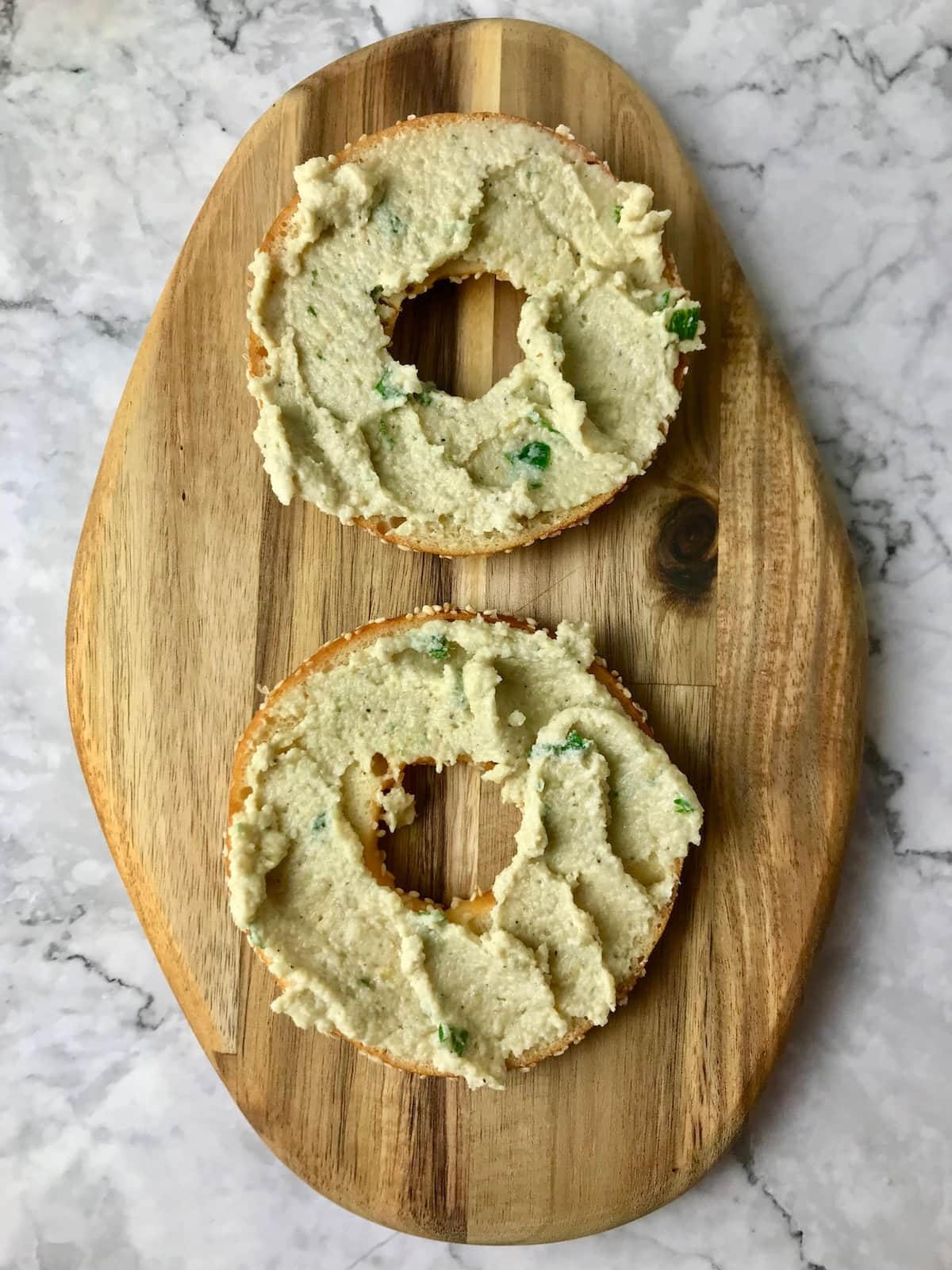 Two bagel slices topped with vegan cream cheese.