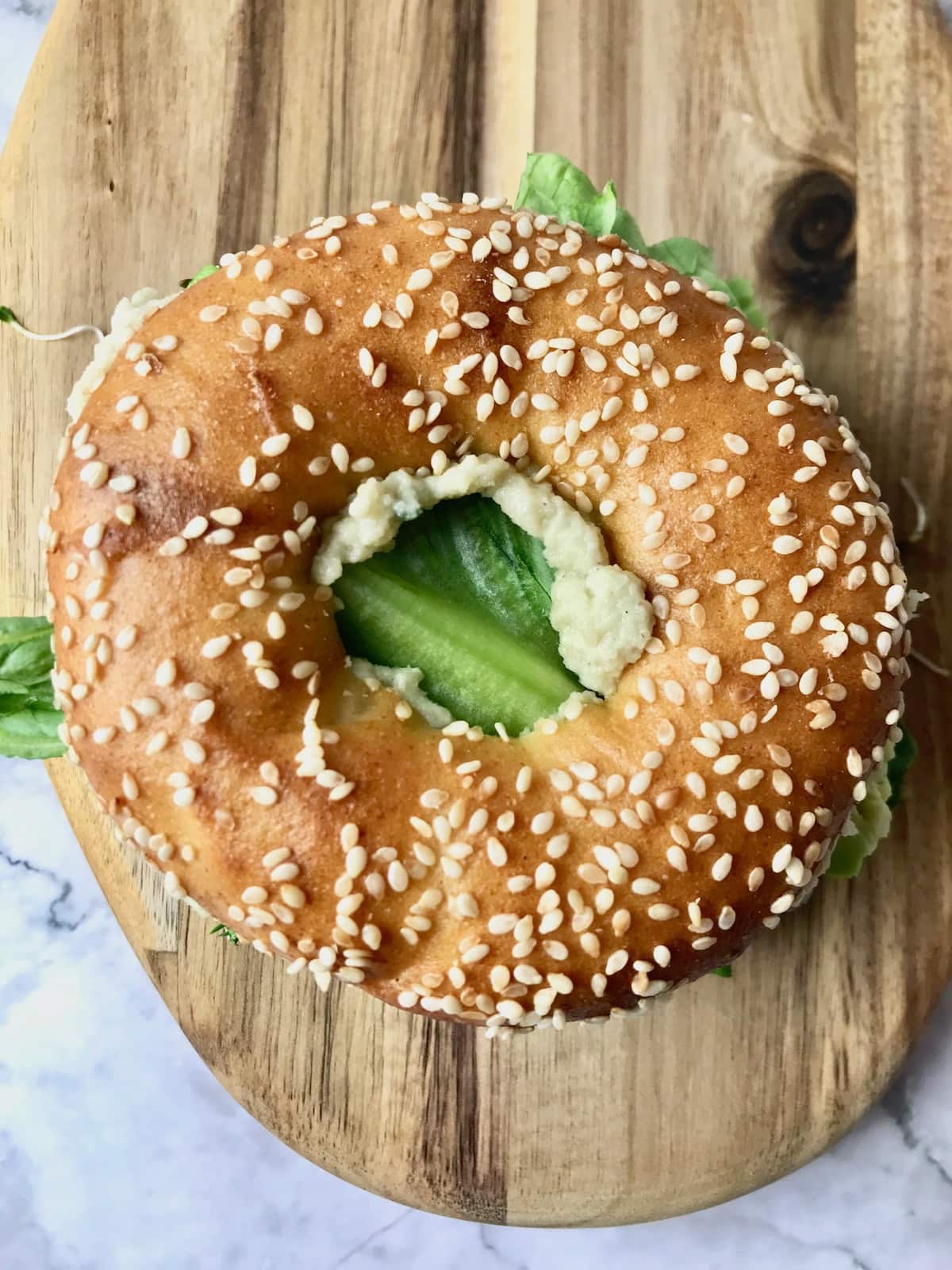 Overhead view of a bagel filled with veggies and vegan cream cheese.