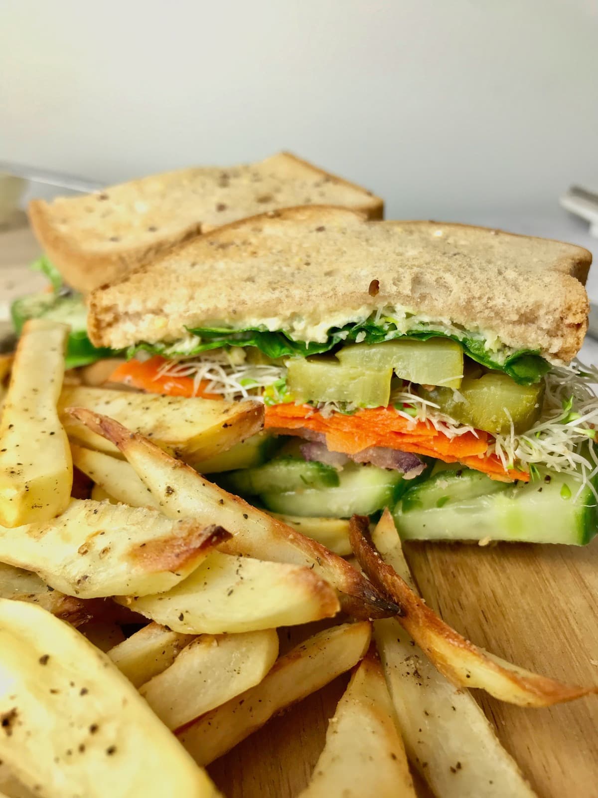 A veggie hummus sandwich next to some fries.