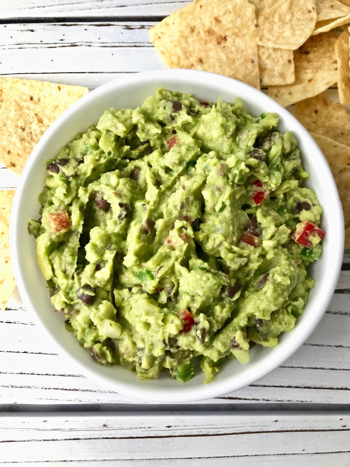 A bowl of guacamole next to some tortilla chips.