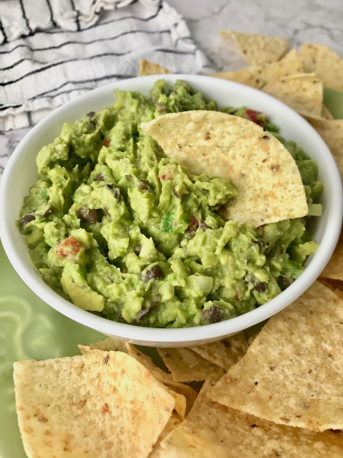 A bowl of black bean guacamole with a chip in it.