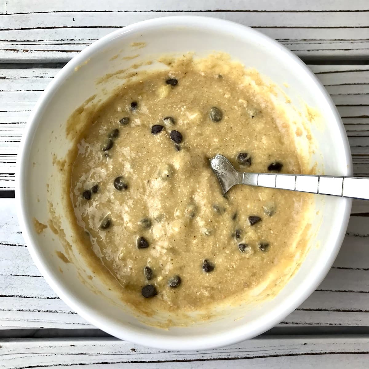 Banana mug cake batter with chocolate chips in a bowl.